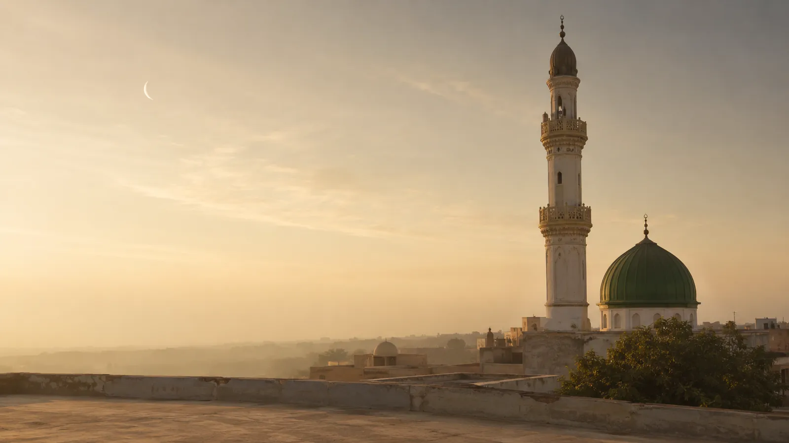 A minaret and dome at first light with a crescent moon